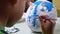 A little girl paints with a brush on the figure of a white pig-shaped papier-mache at home. Make your own piggy bank.