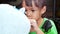 A little girl paints with a brush on the figure of a white pig-shaped papier-mache at home. Make your own piggy bank.