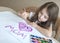 A little girl paints a heart on a homemade greeting card as a gift for Mother Day