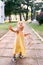 Little girl with a panama hat in her hand looks up, standing on a cobbled walkway