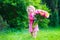 Little girl with peony flowers in the garden