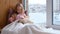 Little Girl Petting Cute Puppy on Windowsill