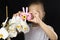 Little girl photographs a white orchid flower with a pink camera in the studio on a dark background