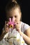 Little girl photographs a white orchid flower with a pink camera in the studio on a dark background