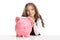 Little girl with a piggybank sitting at a table looking at the c