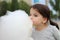 Little girl with pigtails holds in her hand a large ball of cotton candy at a city celebration