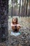 Little girl in the pine forest near the plastic bottle.