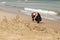Little girl in pink and black wetsuit making sand castles