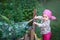 Little girl in pink boots watering the flowers