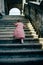 Little girl in pink dress goes up old stairs