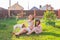 Little girl in pink dress with her mother and jack russell terrier dog on the yard sitting on the grass