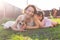 Little girl in pink dress with her mother and jack russell terrier dog on the yard sitting on the grass