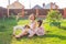 Little girl in pink dress with her mother and jack russell terrier dog on the yard sitting on the grass