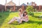 Little girl in pink dress with her mother on the yard sitting on the grass