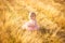 Little girl pink dress sit on sloping  wheat field