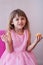 Little girl in pink fancy dress, eating sweet cupcake