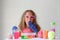 A little girl in pink glasses conducts experiments, looks at the camera . A child in rubber gloves takes a  liquid with a pipette