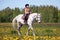 Little girl in pink rides a horse at sunny day