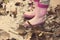 Little girl with pink rubber boots standing in puddle