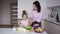 Little girl in pink shirt mixing flour in bowl with her mother on their kitchen. Sweet family. Loving mother kisses her