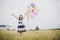 Little girl playing with balloons on meadows field.