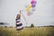 Little girl playing with balloons on meadows field.