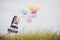 Little girl playing with balloons on meadows field.