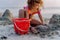 Little girl playing on the beach, building sand castle.