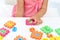 Little girl playing with colorful puzzles at white table, closeup. Educational toy