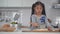 Little girl playing with dough and bakery equipments in home kitchen preparing bakery cooking.