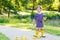 Little girl playing in forest and wearing boots