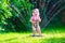 Little girl playing with garden water sprinkler