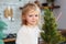 Little girl playing in kitchen with Christmas tree and New Years decor