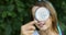 Little girl playing with a magnifying glass in her backyard make faces.