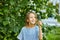 Little girl playing with a magnifying glass in her backyard make faces