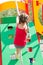 Little girl playing on playground, climbing the wall on rope