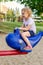 Little girl playing at playground in summer, sitting on carrousel