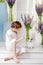 Little girl playing with real rabbit. Child and white bunny on Easter on flower background. Kids and pets play. Fun and friendship