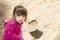 Little girl playing with sand and bucket in sandpit