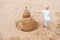 Little girl playing with sand snowman on ocean beach