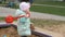 Little girl is playing in a sandbox with a red spatula, close-up