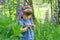 Little girl playing in sunny blooming forest. Toddler child picking lupine flowers. Kids play outdoors. Summer fun for family with