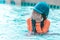 Little girl playing in swimming training pool, wiping water out of her face