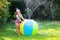 Little girl playing with toy ball garden sprinkler