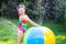 Little girl playing with toy ball garden sprinkler