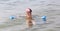 Little girl plays with the floating plastic tube and diving mask