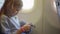 a little girl plays her phone while flying on a plane.