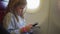 a little girl plays her phone while flying on a plane.