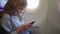 a little girl plays her phone while flying on a plane.