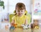 Little girl plays with little toy animals while sitting at table